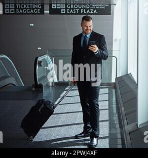 Ill let you know when Ive landed. an executive businessman walking through an airport during a business trip. Stock Photo