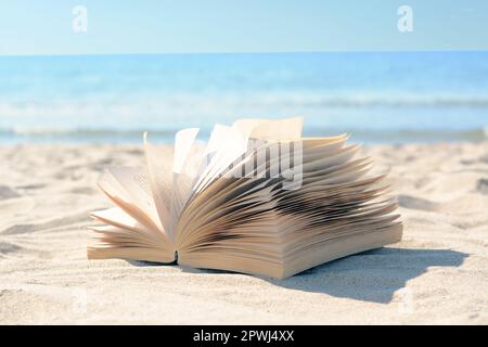 Open book on sandy beach near sea Stock Photo