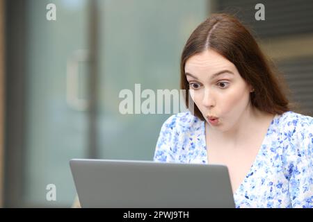 Surprised woman checks laptop sitting in the street Stock Photo