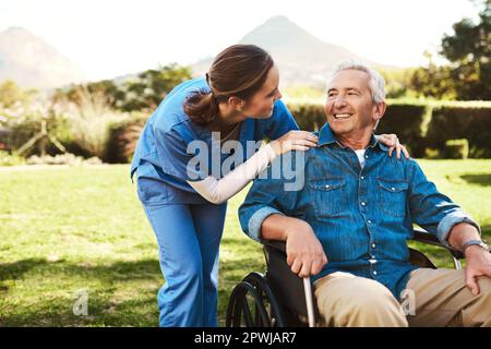 She stood by side through the tough and happy times. a young female nurse outside with a senior patient in a wheelchair Stock Photo