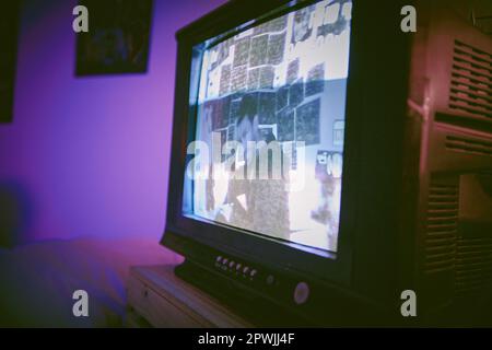 Asian man with mental disorder sitting alone at night feeling paranoid on a television. Mixed race man mentally ill, feeling depressed and holding che Stock Photo