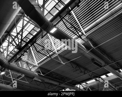 The roof of a hangar, a production hall or a sports hall. Metal structures, beams, supporting elements. Ventilation systems in large halls and rooms. Stock Photo