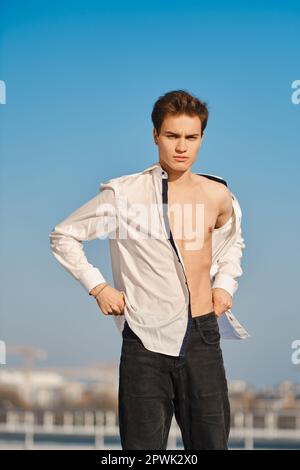 Young man in unfastened white shirt on the street Stock Photo