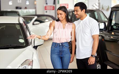I think we can both agree that this is the car for us. a young couple looking at cars at a car dealership Stock Photo