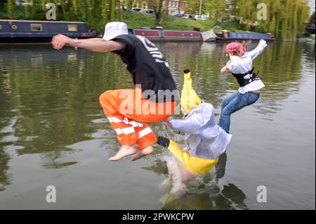 Jesus Green, Cambridge, 30th April 2023 Cambridge University students take the plunge in the River Cam on Sunday afternoon in the Bank Holiday sunshine for the annual 'Caesarian Sunday' drinking party. Undergraduates from the prestigious institution frolicked through the afternoon in fancy dress taking part in drinking games on Jesus Green. The tradition, also known as ‘C-Sunday' attracts thousands of students just before they take part in exams. Police were present to keep the academics in check. Credit: Ben Formby/Alamy Live News Stock Photo