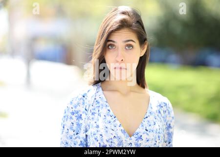 Front view portrait of a perplexed woman looking at camera in the street Stock Photo