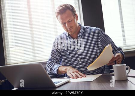 Staying focused on the numbers. a busy businessman using his laptop in the office. Stock Photo