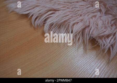 Long pile rug in pink on a beige laminate floor. Feminine interior for