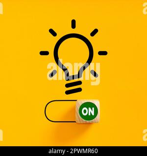 Power on slider button under a light bulb idea symbol on yellow background. Process of finding a creative idea. To generate an idea. Brainstorming and Stock Photo