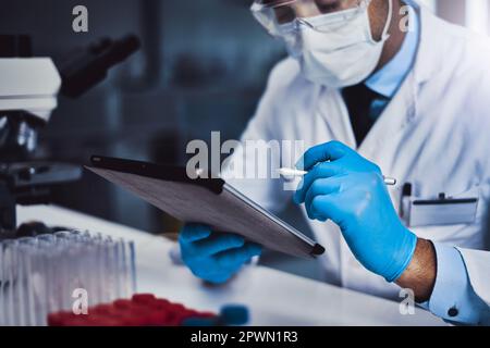 Ordering new lab equipment online. an unrecognizable male scientist working in a lab Stock Photo