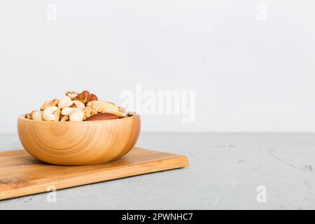 mixed nuts in bowl. Mix of various nuts on colored background. pistachios, cashews, walnuts, hazelnuts, peanuts and brazil nuts. Stock Photo