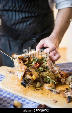 Cook carving a roasted duck with vegetable stuffing Stock Photo
