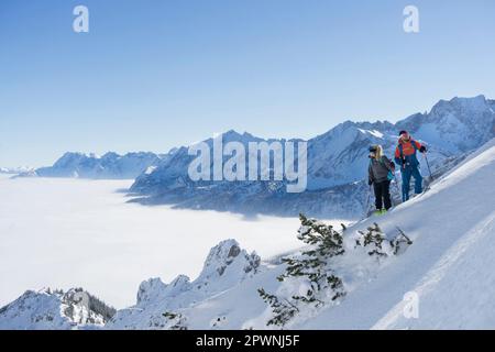 Couple climbing up the ski slope in Upper Bavaria, Germany, Europe Stock Photo