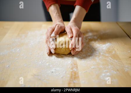 Unrecognizable woman kneads dough with her hands on the table Stock Photo