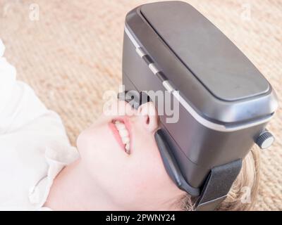 Girl using virtual reality headset while lying on floor Stock Photo