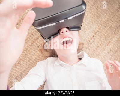 Girl using virtual reality headset while lying on floor Stock Photo