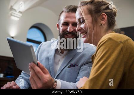 Cheerful couple smiling while using digital tablet at restaurant Stock Photo
