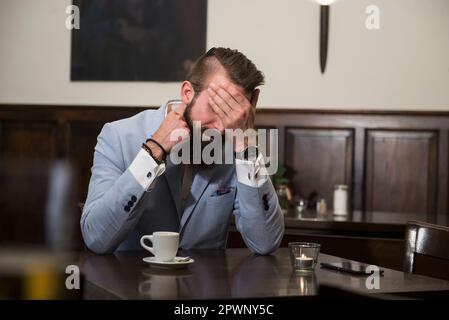 Tired man in suit covering eyes with hand Stock Photo
