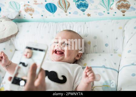 Mother photographing her baby using mobile phone Stock Photo