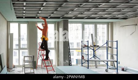 Builder fastens profile using cordless screwdriver Stock Photo