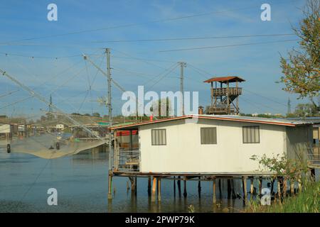 An old white fishing hut against a bright blue sky in the Po Delta in Italy on a May afternoon. Stock Photo