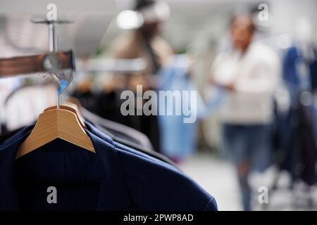 Trendy jackets on hangers in clothing store with blurred background. Casual modern blazers from new collection hanging on rack in department shopping mall close up selective focus Stock Photo