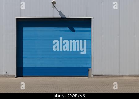 Blue roller shutter entrance to industrial loading area. Stock Photo