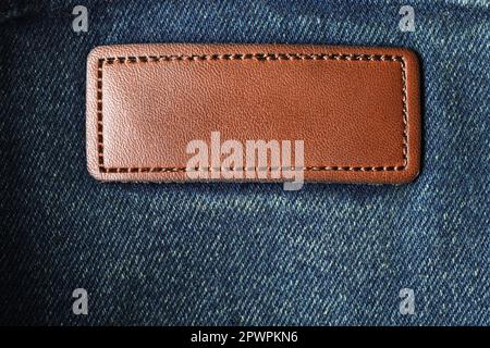 Blank brown leather tag on the dark denim jeans fabric cloth. Stock Photo