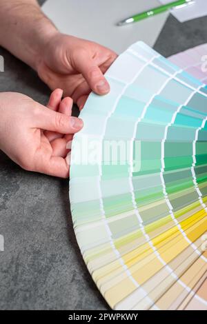 Hands designer or architect choosing swatch the colors painting of the walls in new apartment, showing shades of turquoise design project. Stock Photo