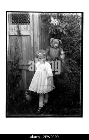 Young Girl and Teddy Bear in Garden Stock Photo