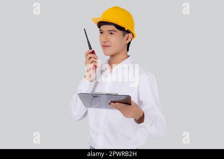 Portrait young asian man is engineer wearing helmet standing and using radio for speak with confident while holding report document isolated on white Stock Photo