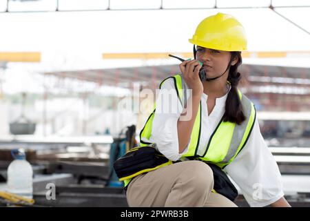 Young woman engineer using radio command with worker in construction site, architect or contractor speak to radio for control and planning development Stock Photo