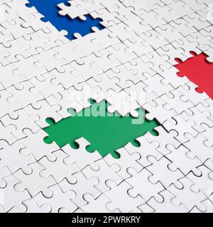 Close-up texture of a white jigsaw puzzle in assembled condition with missing elements, under which surfaces of different colors Stock Photo