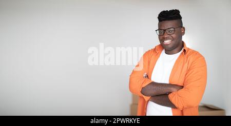 Handsome Black Guy Standing With Folded Arms And Looking At Camera Stock Photo