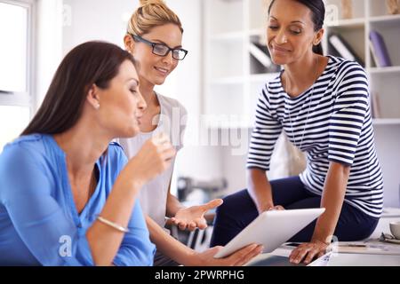 Great minds think alike. Three businesswomen brainstorming ideas while gathered around a digital tablet. Stock Photo