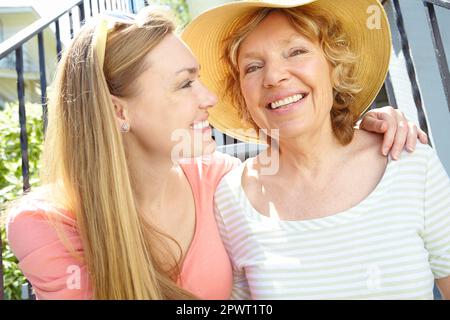 Enjoying the sunshine with her daughter. A happy senior woman smiling widely while spending time with her pretty daughter. Stock Photo