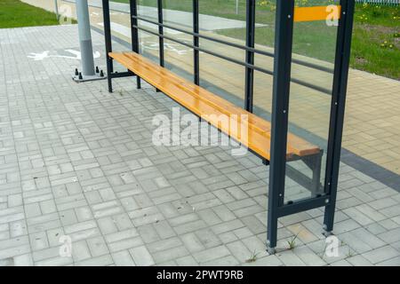 New glass shelter bus stop with wooden bench Stock Photo