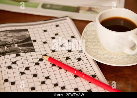 Close-up of the table where someone does a crossword puzzle as hobbies while having a coffee Stock Photo