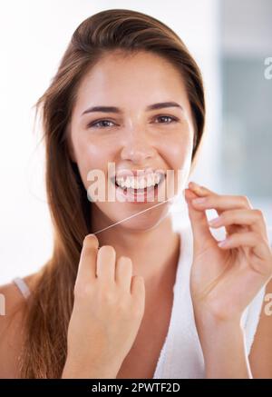 She knows the importance of flossing. Portrait of an attractive young woman holding dental floss and smiling. Stock Photo