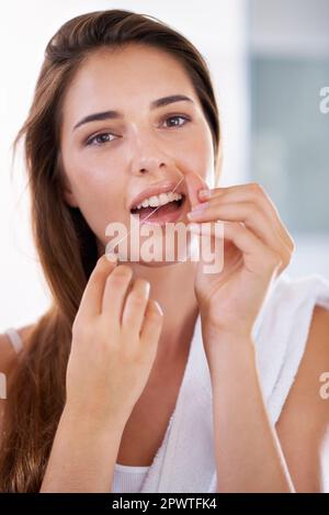 She knows the importance of flossing. Portrait of an attractive young woman holding dental floss and smiling. Stock Photo