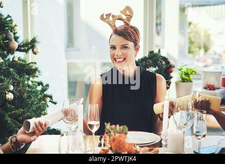 I cant wait to see whats inside. an attractive young woman pulling crackers while having Christmas lunch with her friends at home Stock Photo