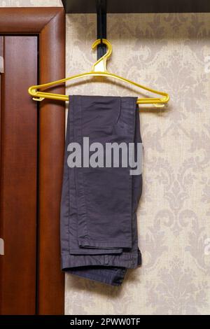 Folded gray trousers hang on a plastic hanger Stock Photo
