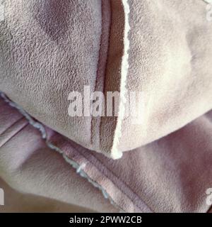 Suede outerwear with a hood. Beige faux suede with sheepskin on the fold of a demi-season garment. seams in the material. Clothing industry and fashio Stock Photo