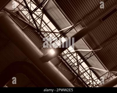 The roof of a hangar, a production hall or a sports hall. Metal structures, beams, supporting elements. Ventilation systems in large halls and rooms. Stock Photo