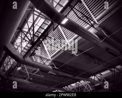 The roof of a hangar, a production hall or a sports hall. Metal structures, beams, supporting elements. Ventilation systems in large halls and rooms. Stock Photo