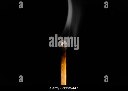 A lit match with smoke on a black background, macro photography. An extinguished match with smoke. Stock Photo