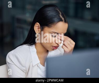 How am I going to recover from this. an attractive young businesswoman sitting alone in her office at night and feeling stressed while using her compu Stock Photo