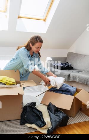 Brunette woman packing donation, concept of charity. Stock Photo