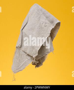 Folded gray linen tea towel on a yellow background, close up Stock Photo