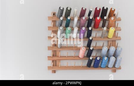 A collection of multi coloured sewing threads displayed on a wooden, wall mounted spool thread rack, set against a white background with copy space Stock Photo